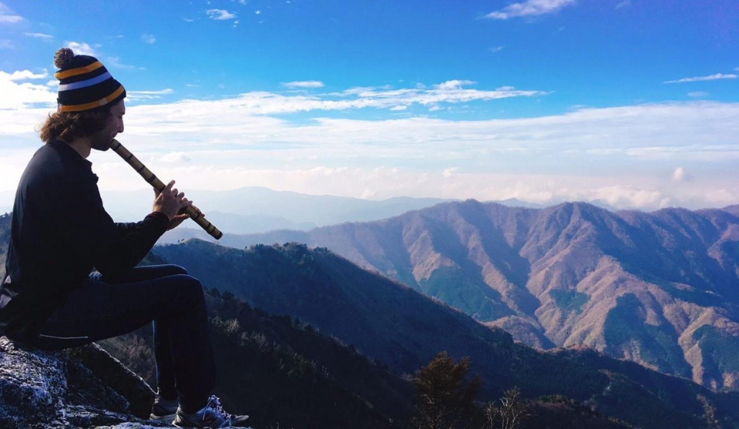 Student playing an instrument on a mountain top